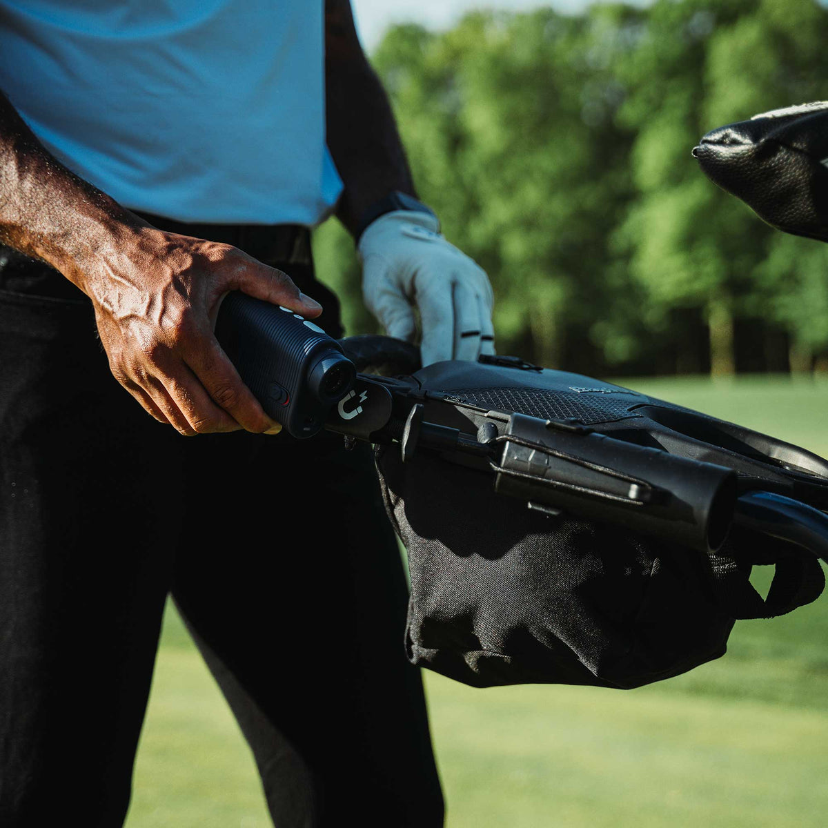 Golfer using the Bag Boy Quad Pro handle and accessory bag on the course