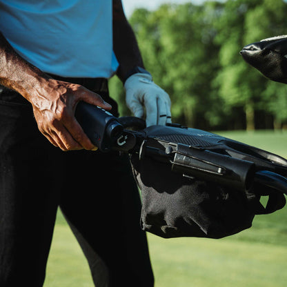 Golfer using the Bag Boy Quad Pro handle and accessory bag on the course