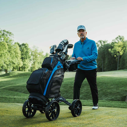 Golfer pushing a Black/Slate Bag Boy Quad Pro push cart with a golf bag on the course